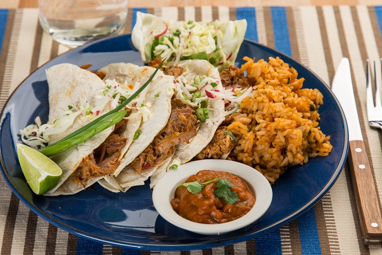 Pork carnitas tacos on flour tortillas with cabbage slaw, Spanish rice and salsa.