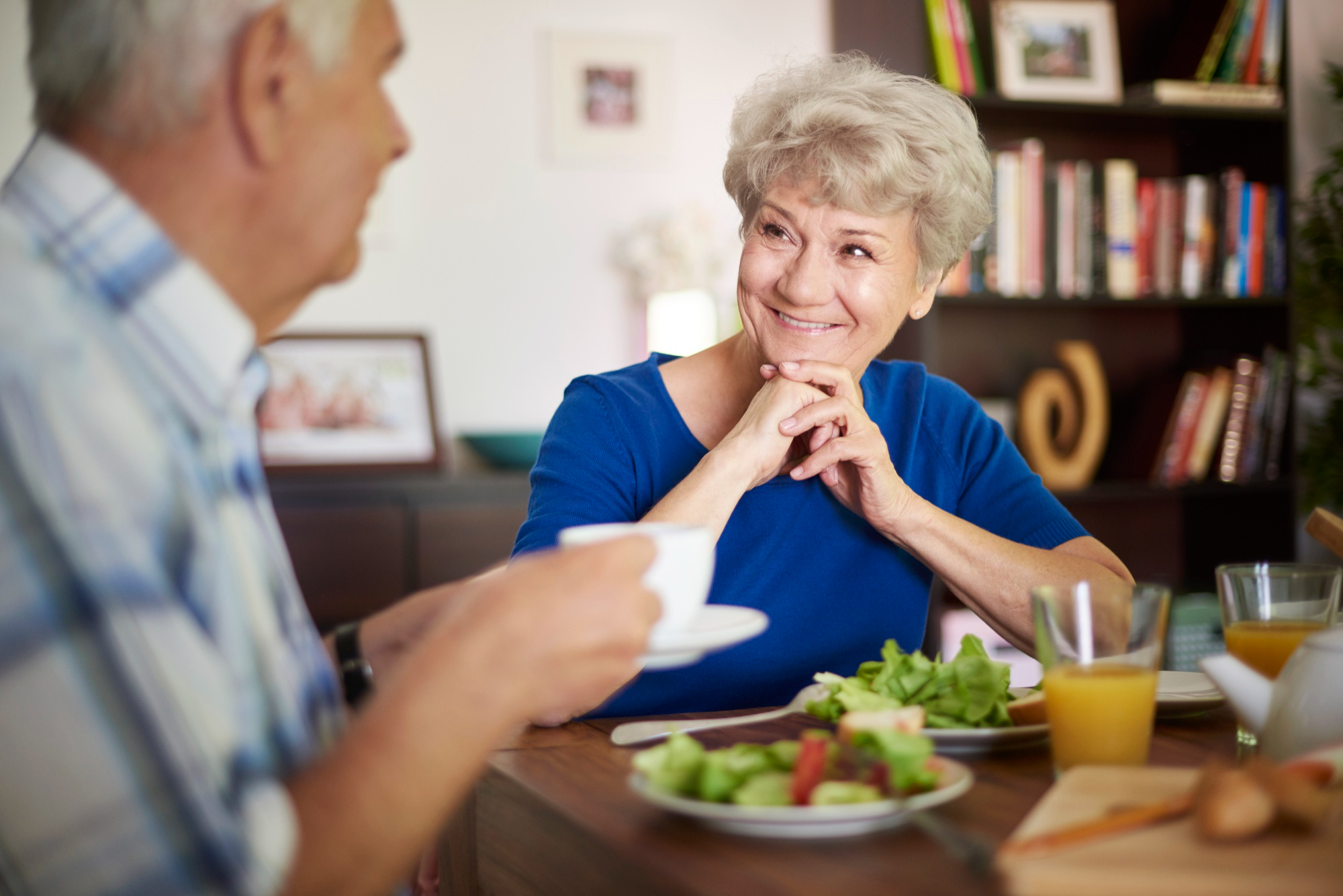 senior man standing at a dining table where the family is seated, enjoying a home-cooked meal